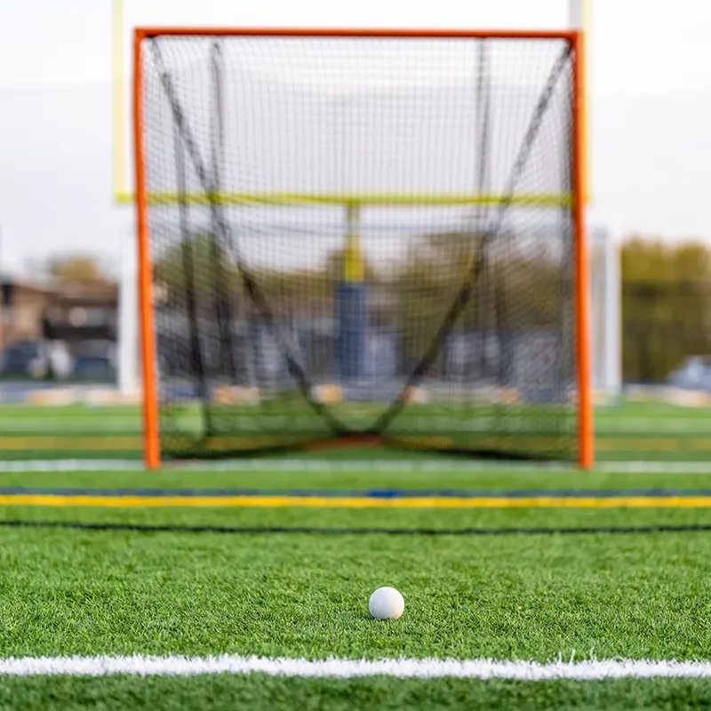 Lacrosse Lacrosse ball on turf grass in front of lacrosse net